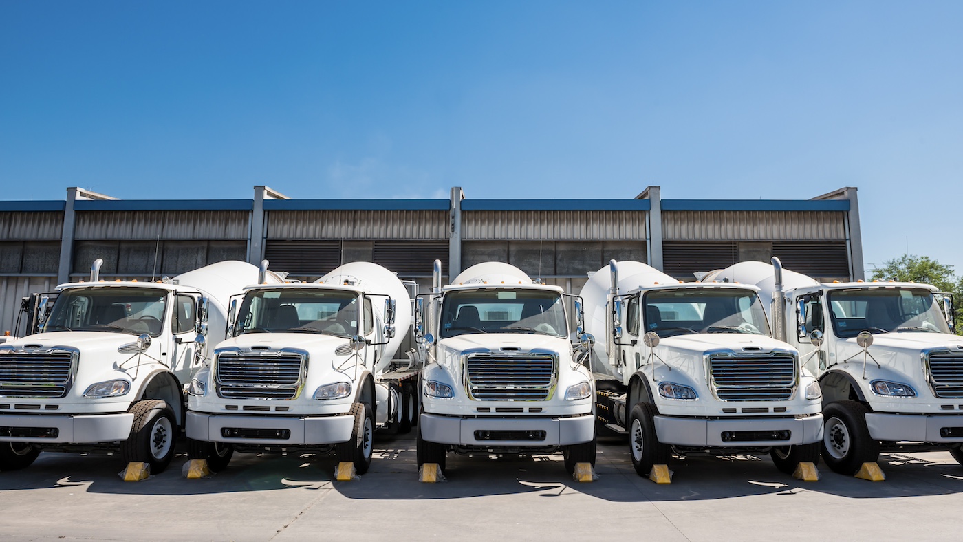 a fleet of cement trucks in a row under blue sky